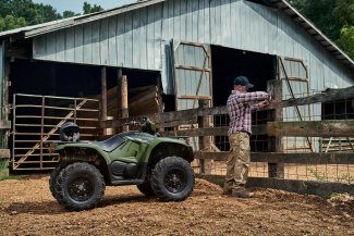 A man fixing a fence next to his ATV