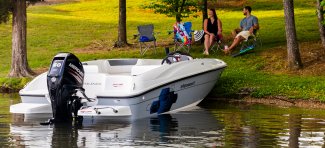 A couple sitting on the grass looking at their Bayliner Element E16